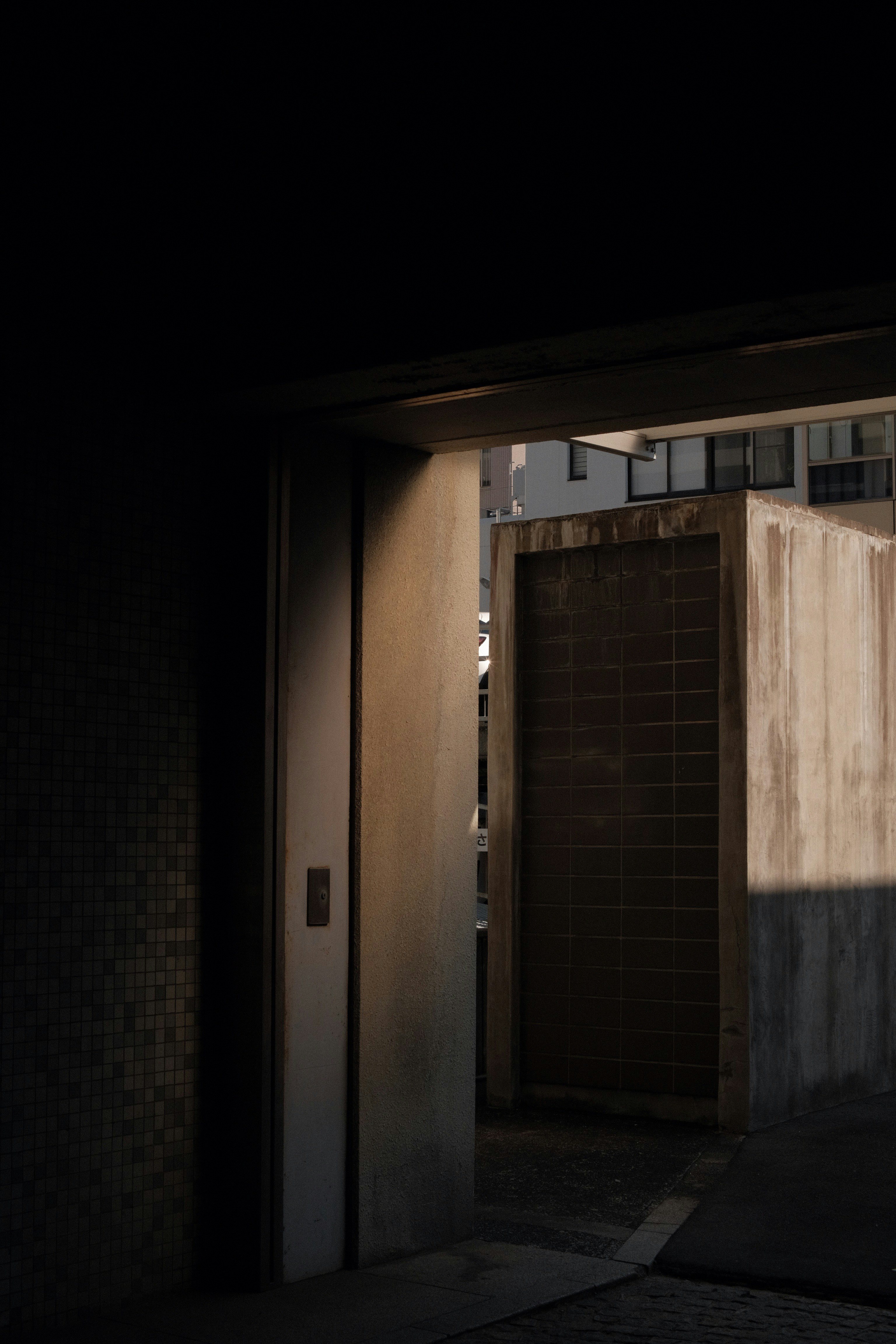 an open door in a dark room with a building in the background